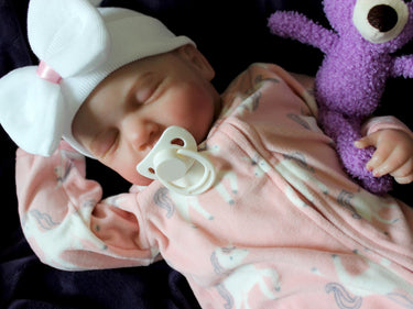 A baby doll resting on a soft purple couch, showcasing its delicate features and bright clothing.
